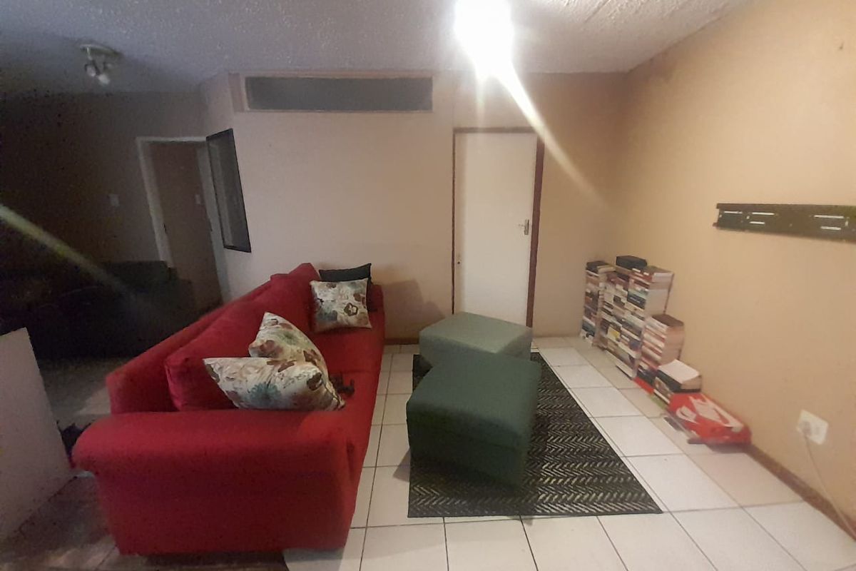 A living room area featuring tiled flooring and textured ceilings, requiring cosmetic updates to improve the overall aesthetic and condition of the space.