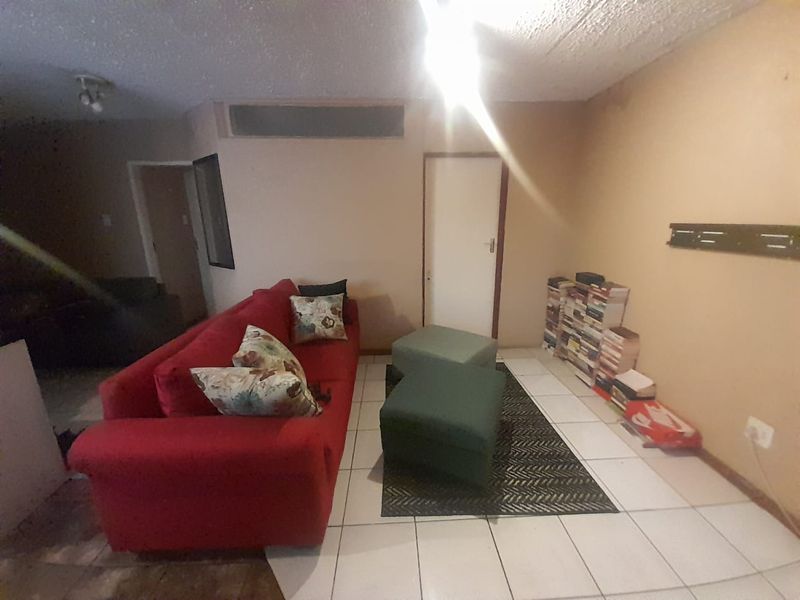 A living room area featuring tiled flooring and textured ceilings, requiring cosmetic updates to improve the overall aesthetic and condition of the space.