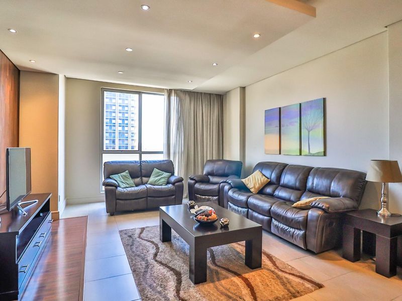 A well-maintained living room featuring tiled flooring, recessed ceiling lighting, and a large window providing natural light.