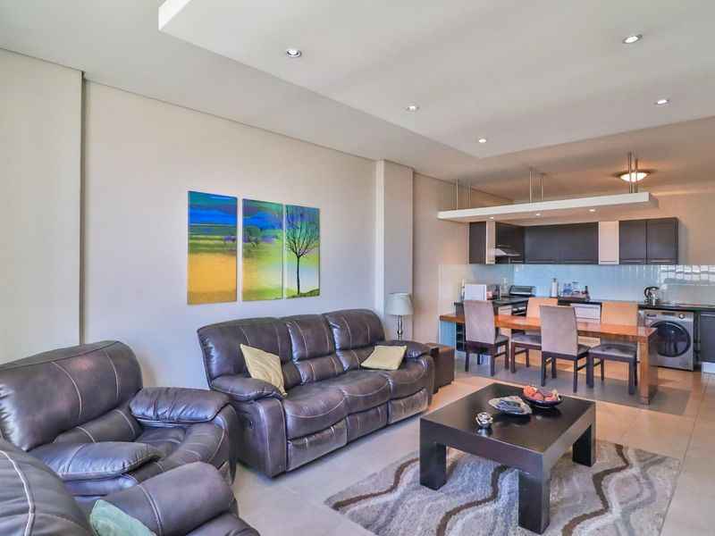 Modern open-plan living area featuring a well-appointed kitchen with built-in cabinetry, integrated breakfast bar, and recessed ceiling lighting throughout the space.