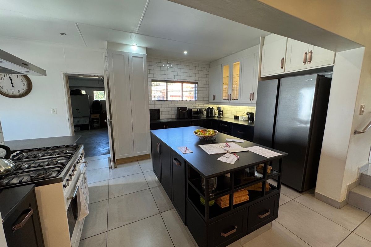 Modern kitchen featuring a central island, subway tile backsplash, built-in cabinetry, and a gas stove, with an adjacent doorway leading to a utility area.