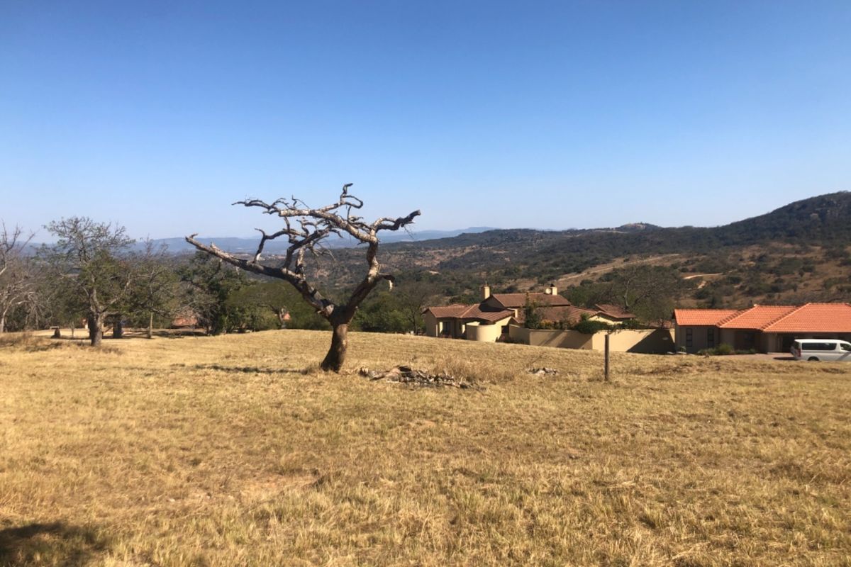 A scenic view of the vacant residential land featuring natural landscape, rolling hills, and surrounding estate properties.