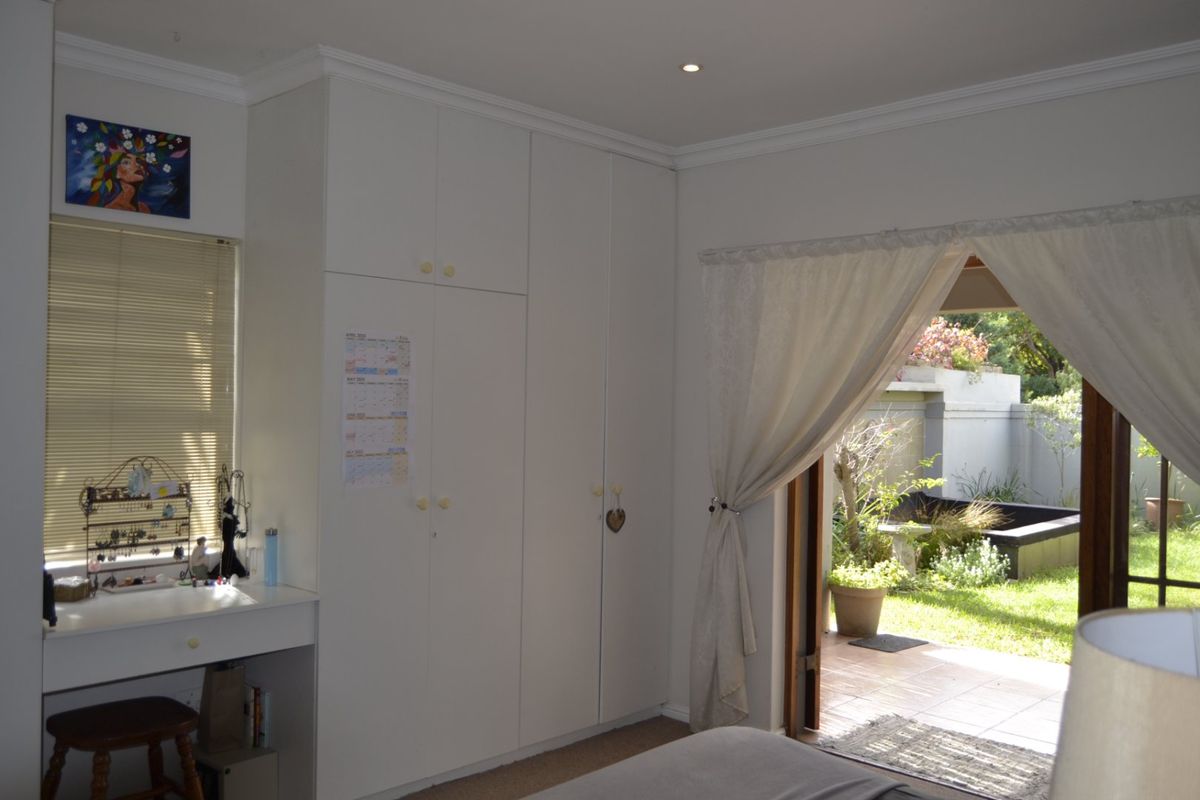 Bedroom featuring built-in cupboards, a vanity area, and direct access to a private garden patio through sliding glass doors.