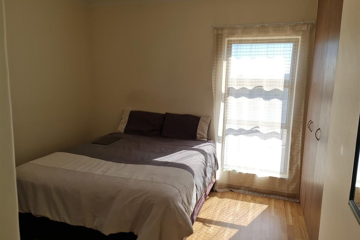 A functional bedroom featuring laminate flooring and a built-in wardrobe, providing essential storage space.