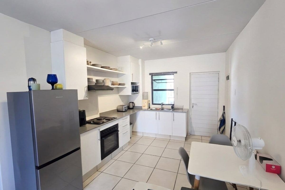 A functional kitchen featuring white cabinetry, tiled flooring, a built-in oven, and a hob, offering a clean and practical layout.