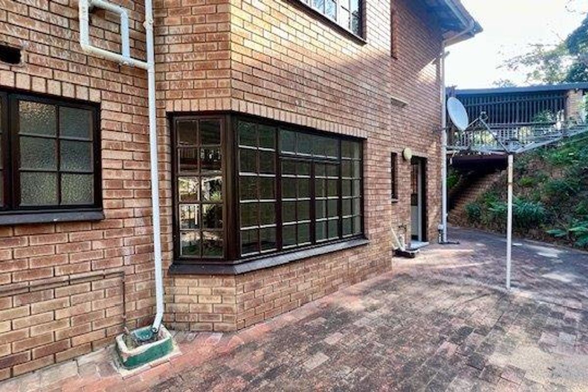 Exterior view of the townhouse featuring face-brick facade, multi-pane windows, and a paved rear courtyard area.