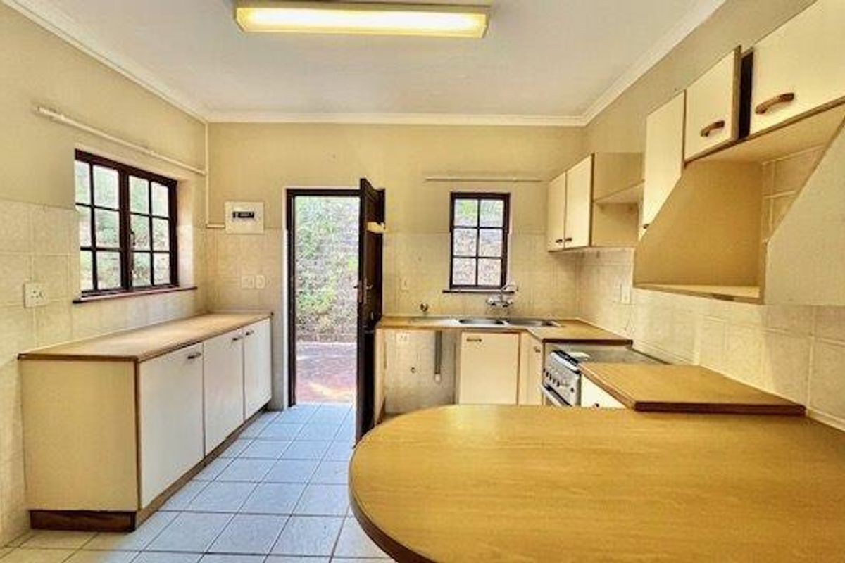 A functional kitchen featuring built-in cabinetry, a double sink, tiled flooring, and direct access to an outdoor area.