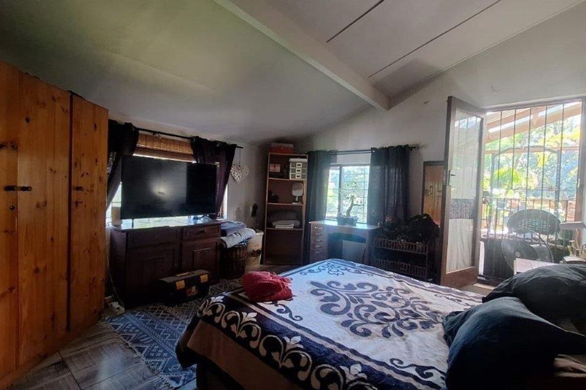 A bedroom featuring tiled flooring, a built-in wardrobe, and direct access to an outdoor area through a security-gated door.