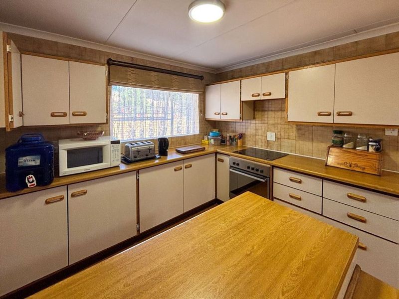 A functional kitchen featuring laminate countertops, built-in cabinetry, and integrated cooking appliances with a tiled backsplash.