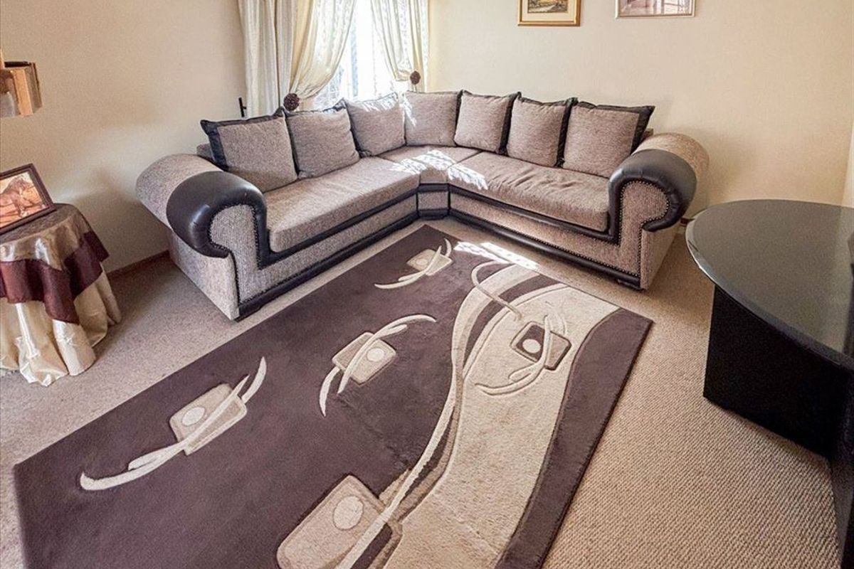 A carpeted living room featuring neutral wall tones and window treatments, providing a functional and comfortable space for relaxation.