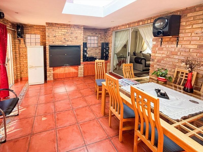 Enclosed patio area featuring exposed brick walls, a built-in braai, tiled flooring, and a large skylight, providing a versatile indoor-outdoor entertainment space.