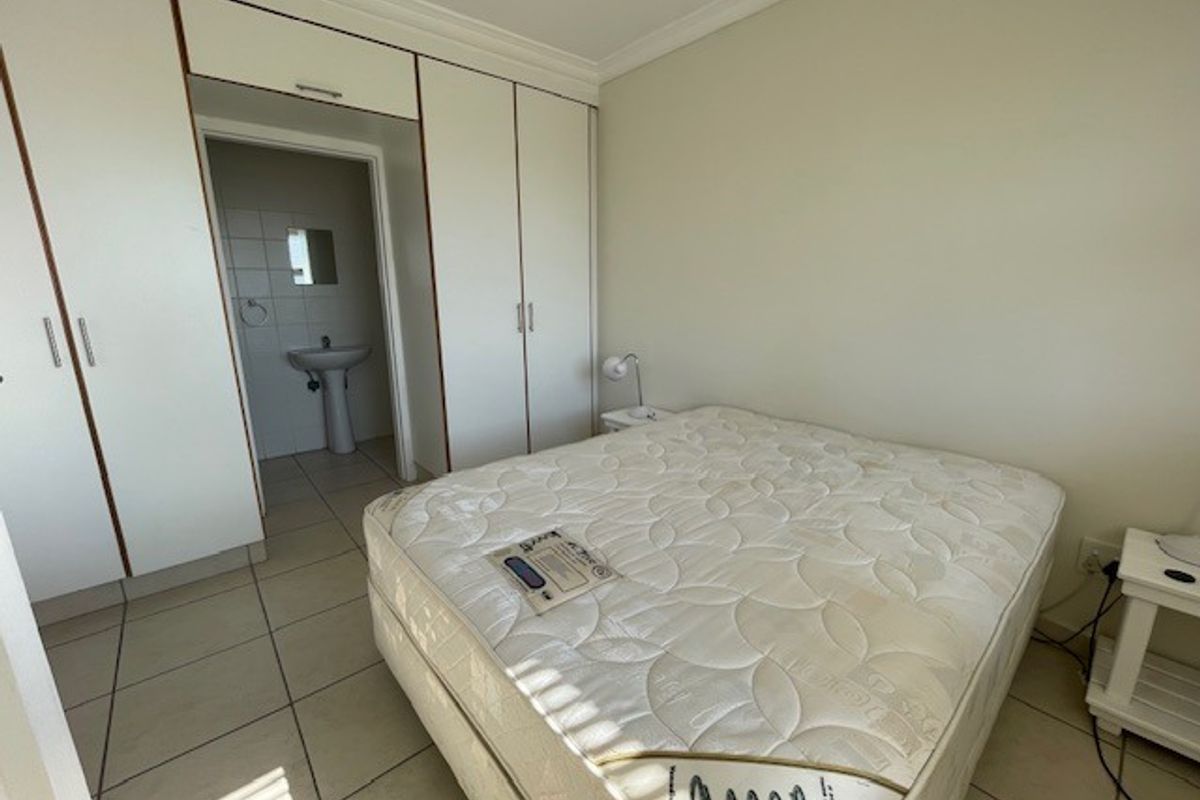 Bedroom featuring built-in cupboards, tiled flooring, and an en-suite bathroom area with a pedestal basin.