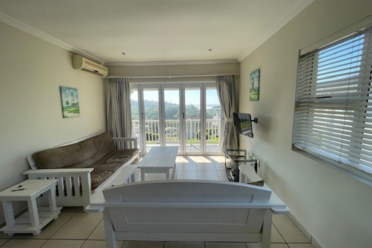 A bright living room featuring tiled floors, split-system air conditioning, and large sliding doors that open to a scenic outdoor view.