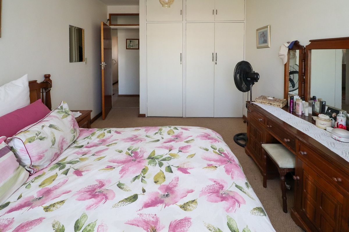 A bedroom featuring built-in cupboards with white doors and carpeted flooring, providing functional storage space.