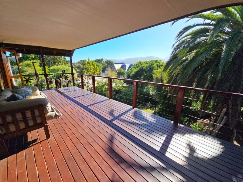 Spacious covered timber balcony featuring stainless steel cable balustrades and elevated views of the surrounding garden and neighbourhood.