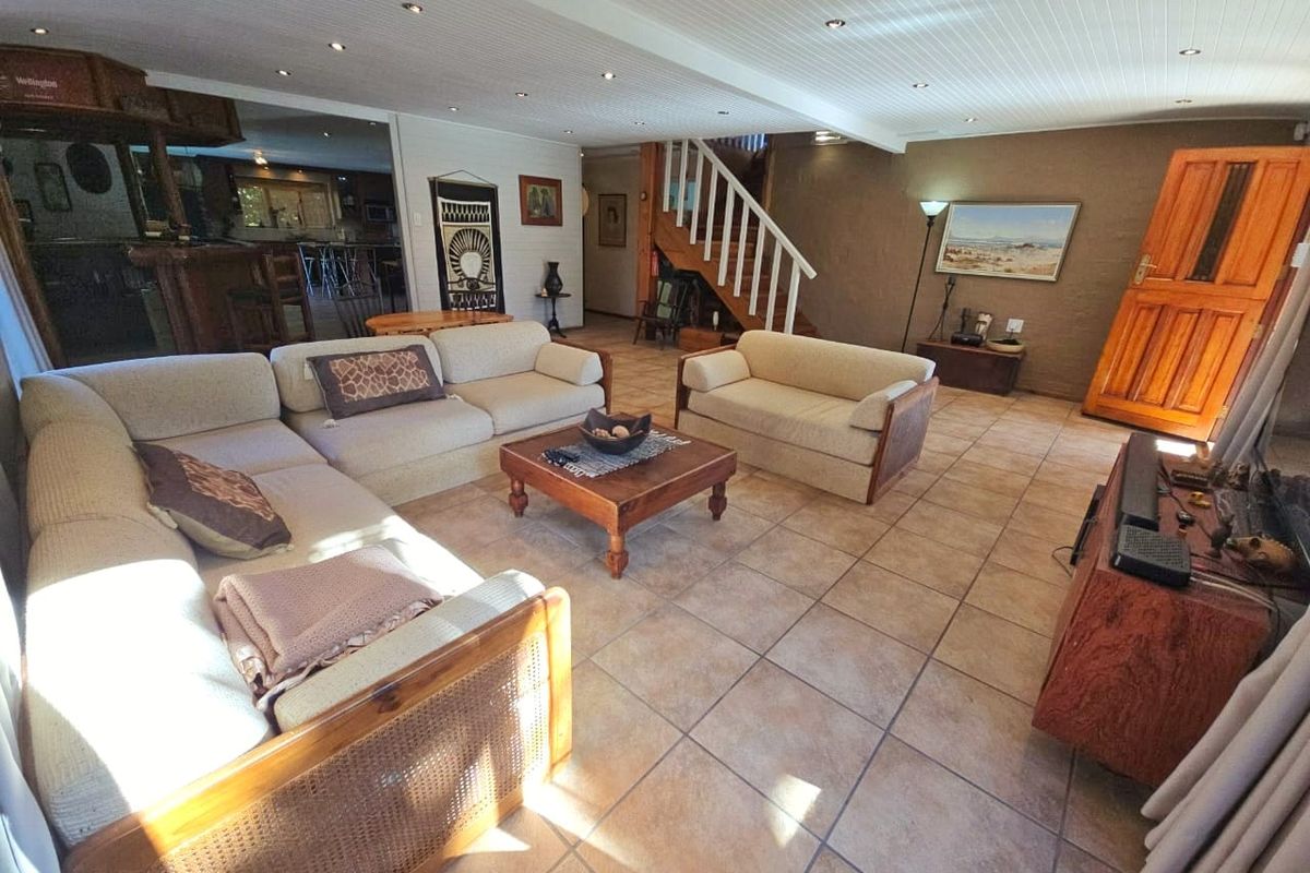 Spacious living area featuring tiled flooring, recessed ceiling lighting, and a wooden staircase leading to the upper level.