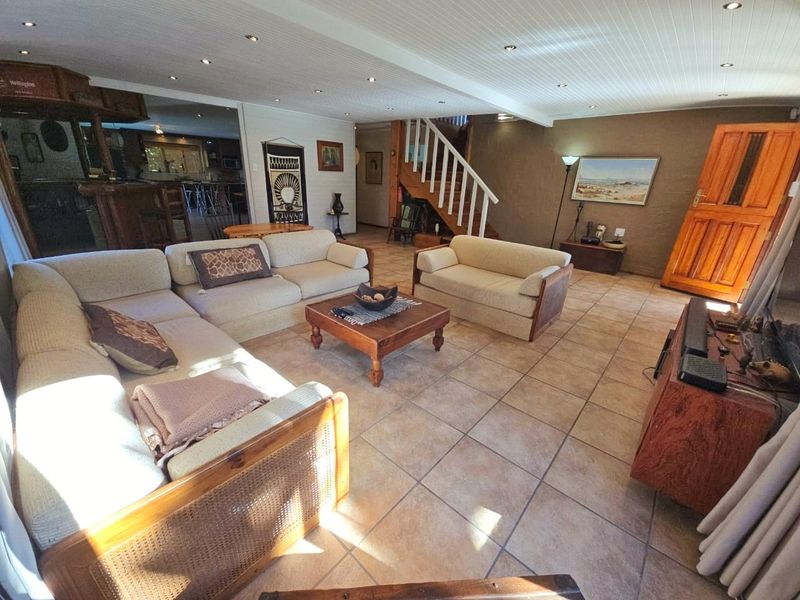 Spacious living area featuring tiled flooring, recessed ceiling lighting, and a wooden staircase leading to the upper level.