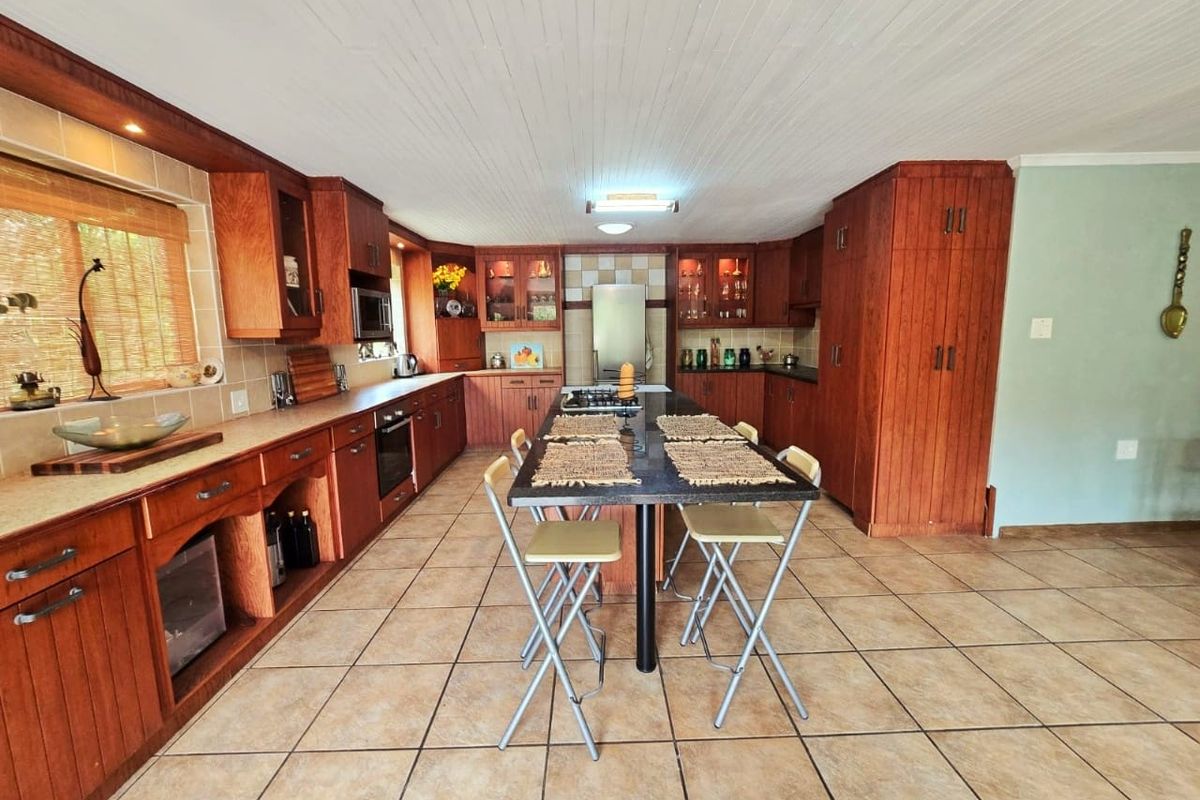 Spacious kitchen featuring extensive wooden cabinetry, a central island with seating, tiled flooring, and a classic tongue and groove ceiling.