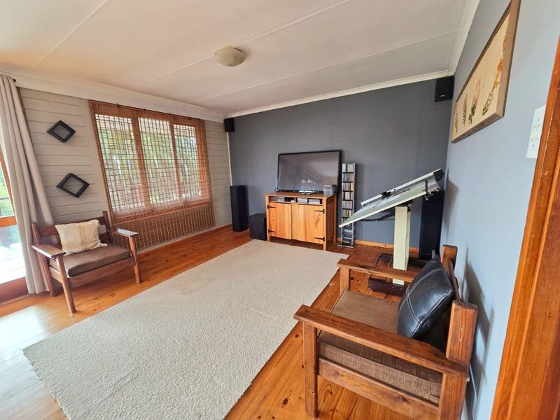 A living room featuring polished timber flooring, a coved ceiling, and a sliding glass door providing natural light.