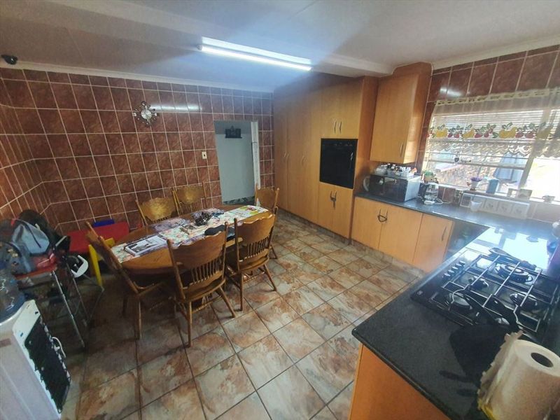 Open-plan kitchen and dining area featuring dated cabinetry, tiled surfaces, and integrated cooking appliances, offering potential for a modern renovation.