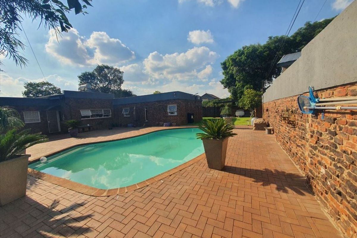 Outdoor pool area featuring brick paving, an exposed brick boundary wall, and a swimming pool with a solar water heater system.
