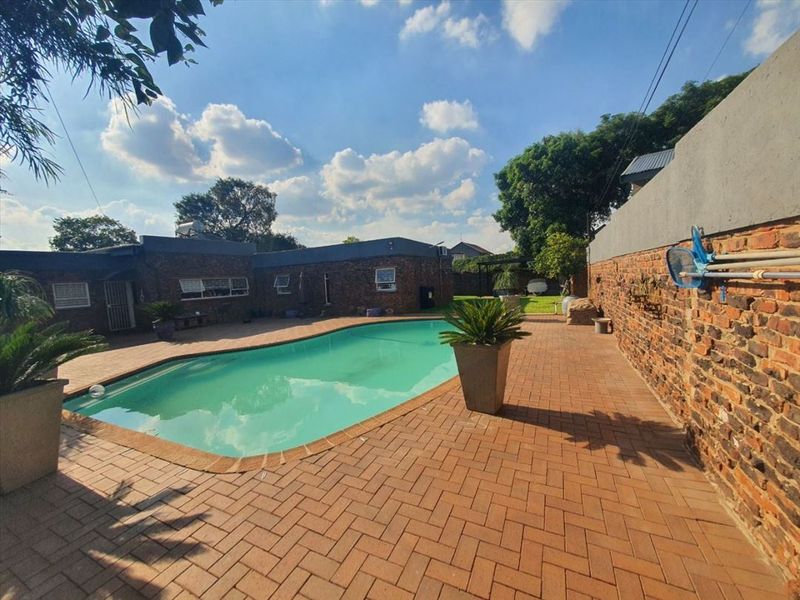 Outdoor pool area featuring brick paving, an exposed brick boundary wall, and a swimming pool with a solar water heater system.