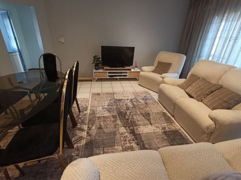 An open-plan living and dining area featuring tiled flooring and neutral wall finishes, providing a functional space for relaxation and meals.