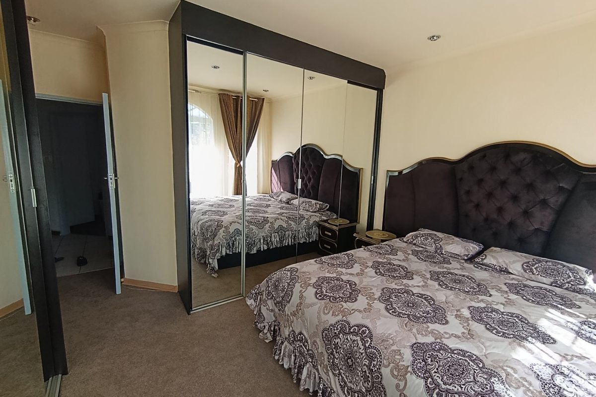 A well-maintained bedroom featuring a large built-in mirrored wardrobe, recessed ceiling lighting, and neutral carpeting.