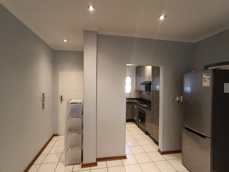 A functional kitchen area featuring tiled flooring, built-in cabinetry, and integrated appliances, with an adjacent entryway and intercom system.