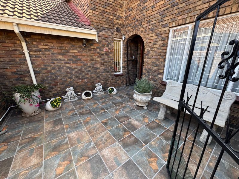 A private paved patio area featuring classic brickwork, secure gated access, and durable tiled flooring, offering a low-maintenance outdoor space.