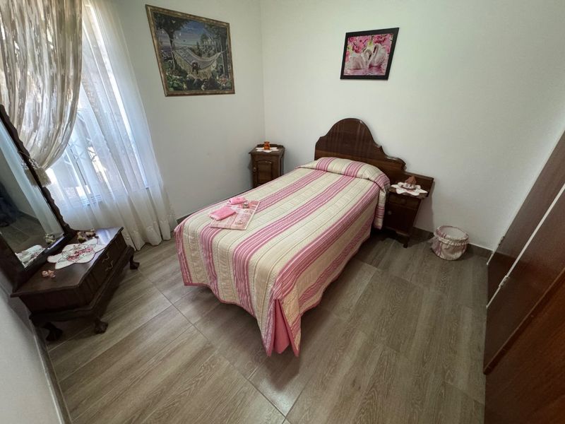 A cozy bedroom featuring wood-look tiled flooring and a built-in wardrobe, offering a functional and well-maintained living space.