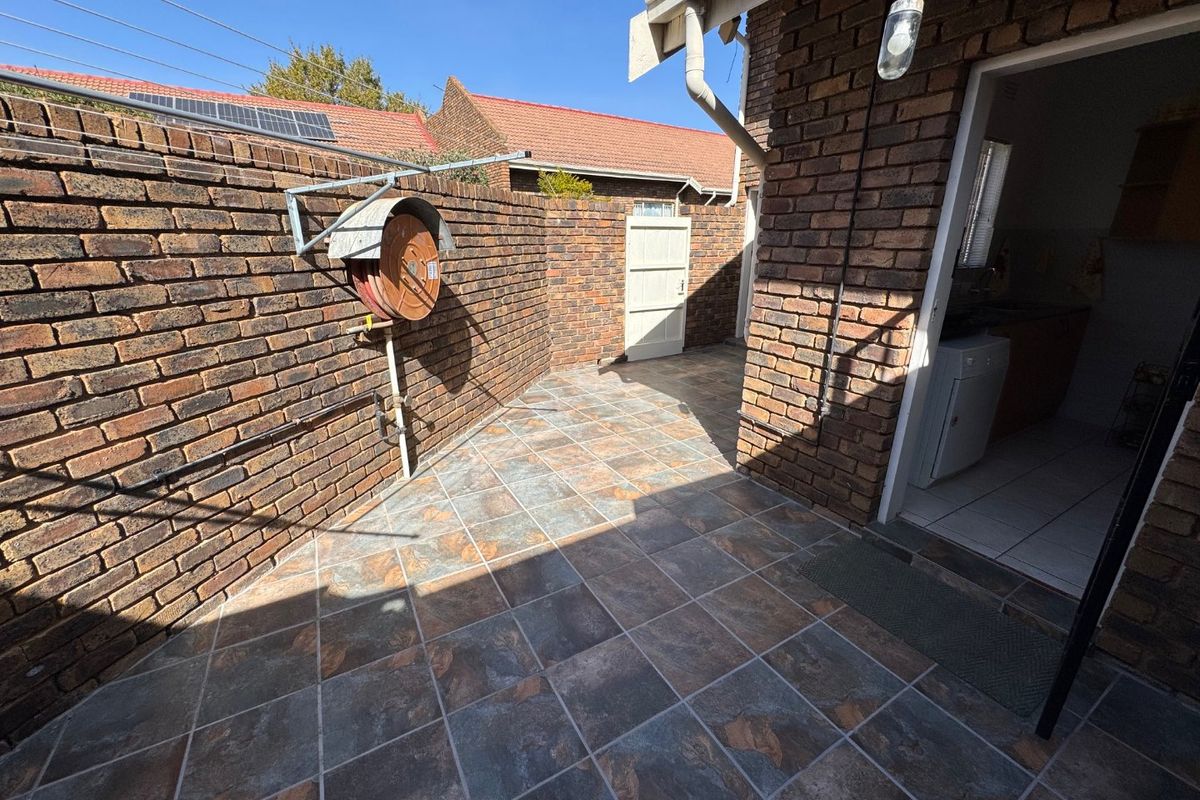 A private rear courtyard featuring durable brick walls, tiled flooring, and direct access to the interior utility area.