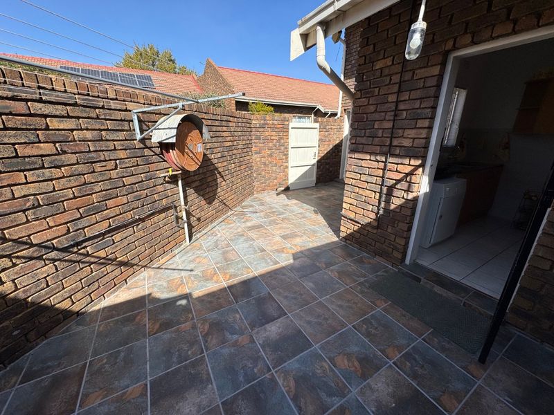 A private rear courtyard featuring durable brick walls, tiled flooring, and direct access to the interior utility area.