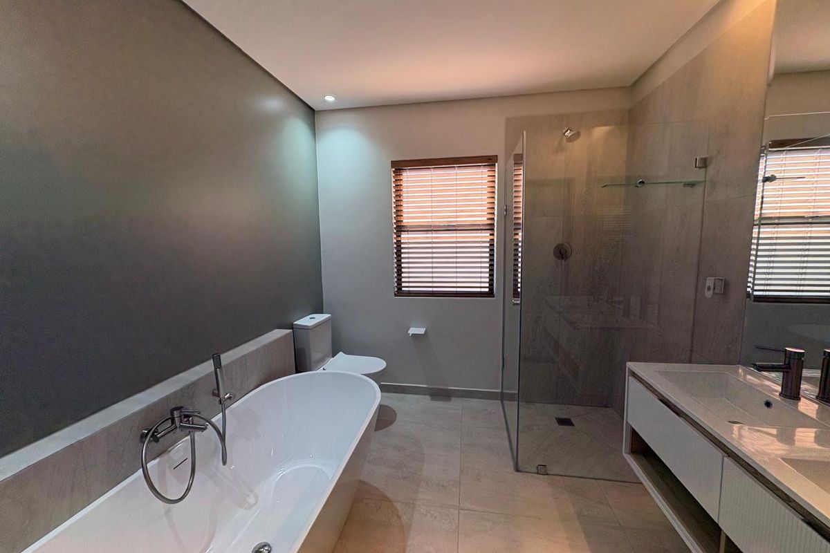 Modern bathroom featuring a sleek freestanding bathtub, a spacious walk-in shower with glass enclosure, and a contemporary wall-mounted vanity unit.