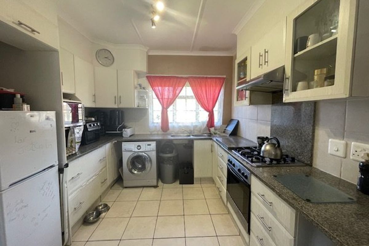 Functional kitchen featuring granite countertops, built-in gas hob, electric oven, extractor fan, and tiled flooring with ample storage cabinetry.