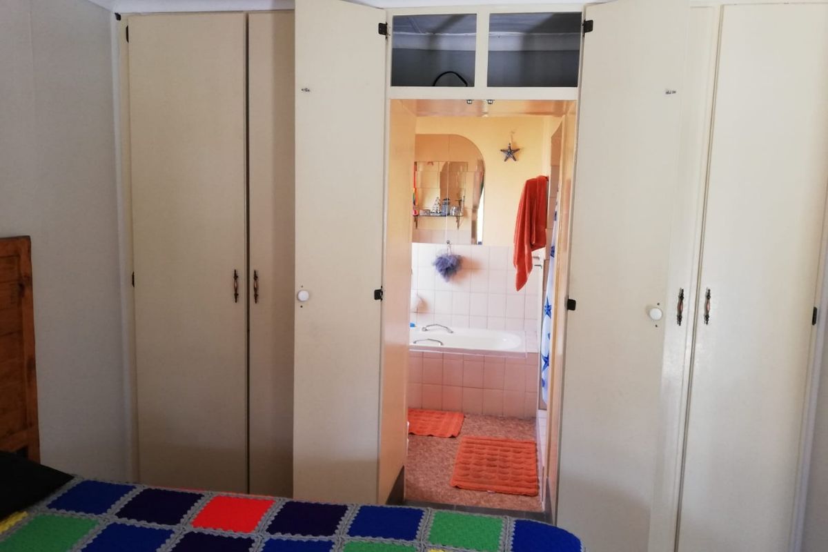 Bedroom featuring extensive built-in cupboards with overhead storage and direct access to an en-suite bathroom.