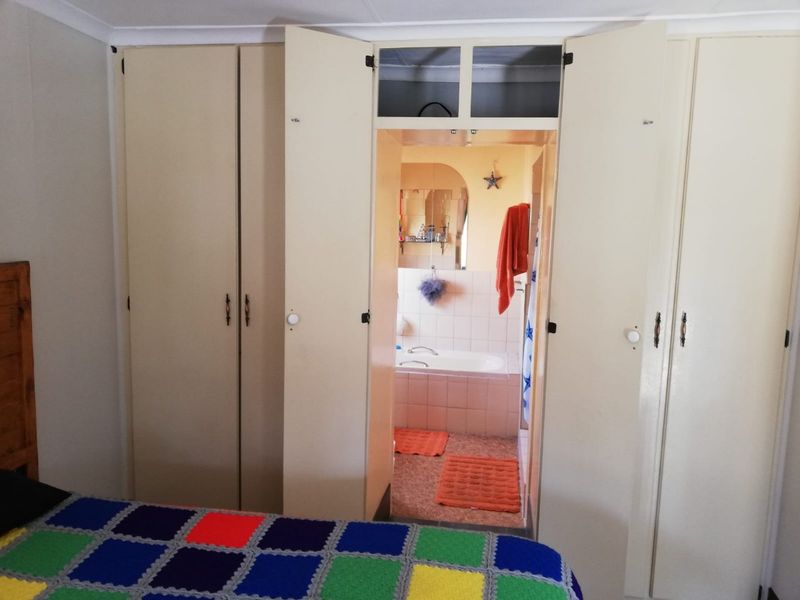 Bedroom featuring extensive built-in cupboards with overhead storage and direct access to an en-suite bathroom.