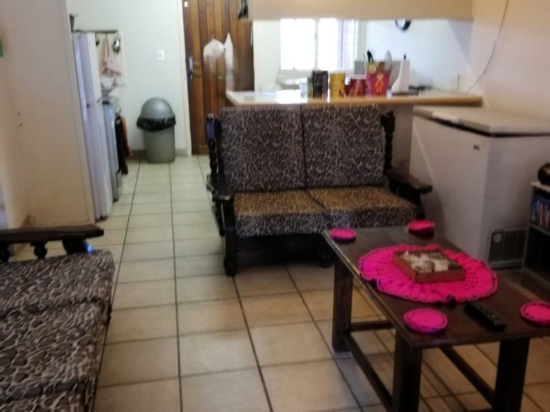 Open plan living area featuring tiled flooring, a breakfast bar, and a wall-mounted air conditioning unit.