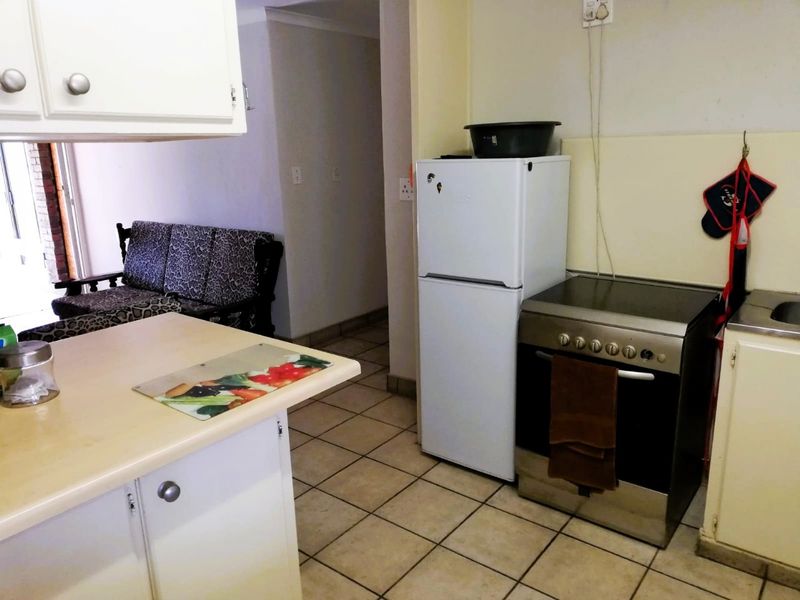 A compact kitchen area featuring tiled flooring, built-in cabinetry, and a freestanding oven, offering a functional layout with potential for modernization.