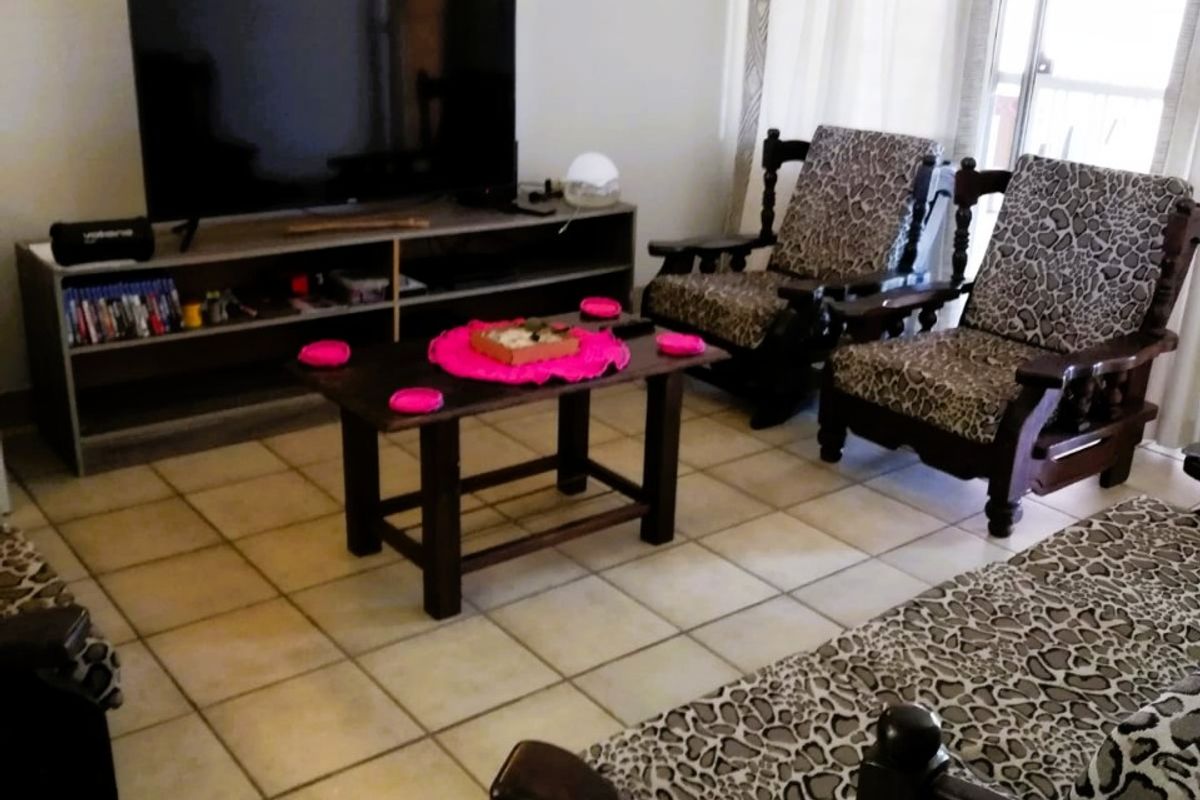 A living room featuring tiled flooring and a sliding glass door providing natural light.