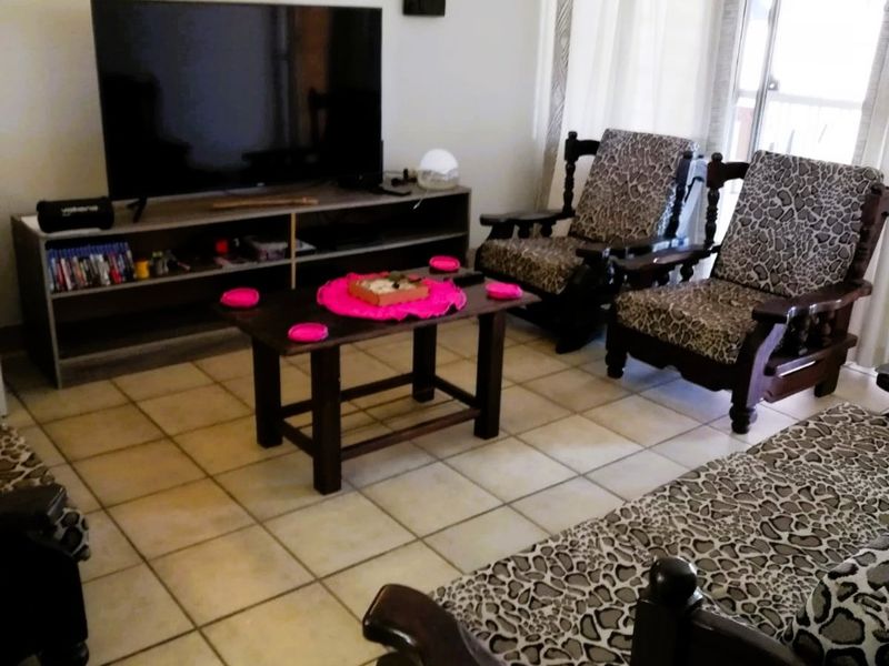 A living room featuring tiled flooring and a sliding glass door providing natural light.