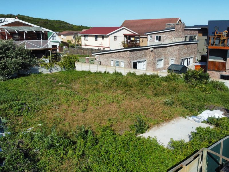 Aerial view of a vacant residential plot featuring overgrown vegetation, a concrete slab foundation, and surrounding boundary walls in a developed neighborhood.