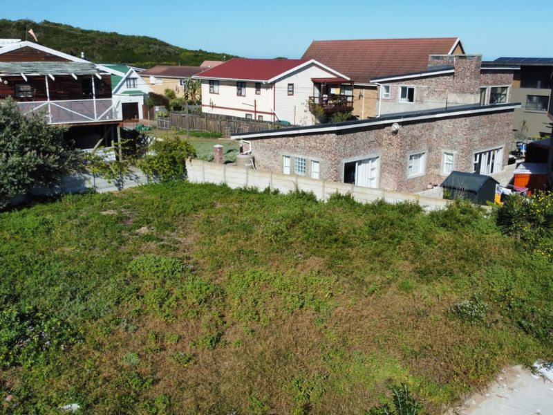 Aerial view of a vacant residential plot featuring overgrown vegetation and enclosed by a precast concrete boundary wall in a developed neighborhood.