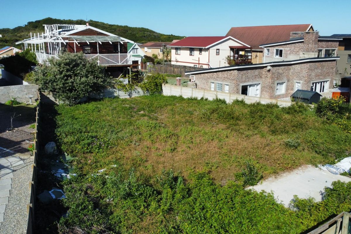 An elevated view of a vacant residential plot featuring a concrete slab foundation and perimeter boundary walls, surrounded by established residential properties.