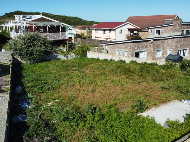 An elevated view of a vacant residential plot featuring a concrete slab foundation and perimeter boundary walls, surrounded by established residential properties.