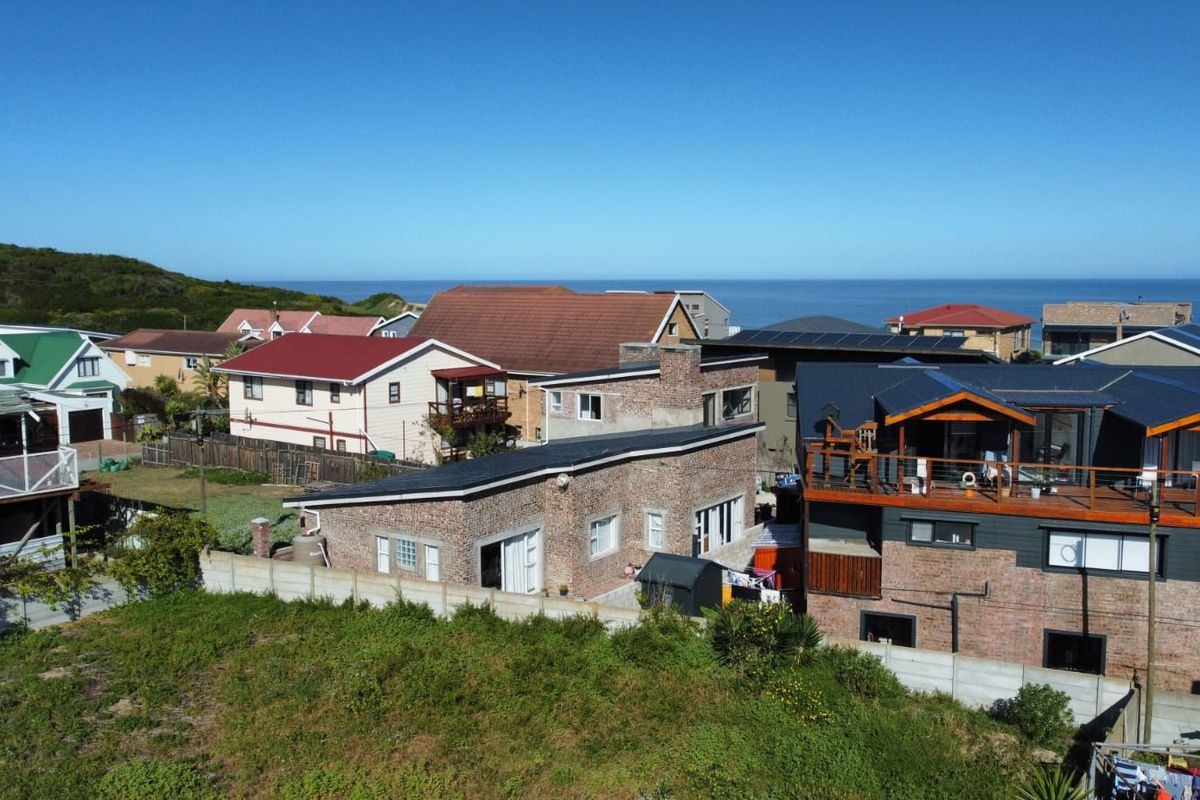 Aerial view of a residential neighborhood featuring brick homes, pitched roofs, and coastal proximity.