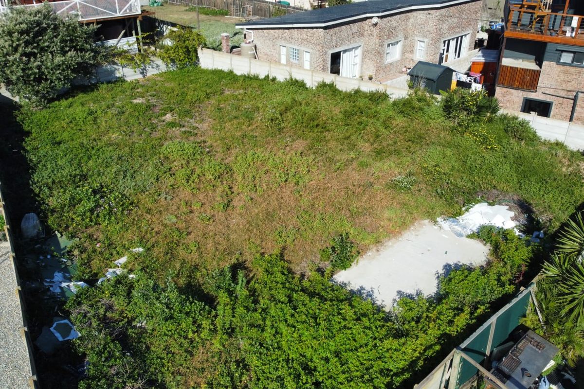 Aerial view of a vacant residential plot featuring overgrown vegetation and a concrete slab foundation, enclosed by boundary walls.