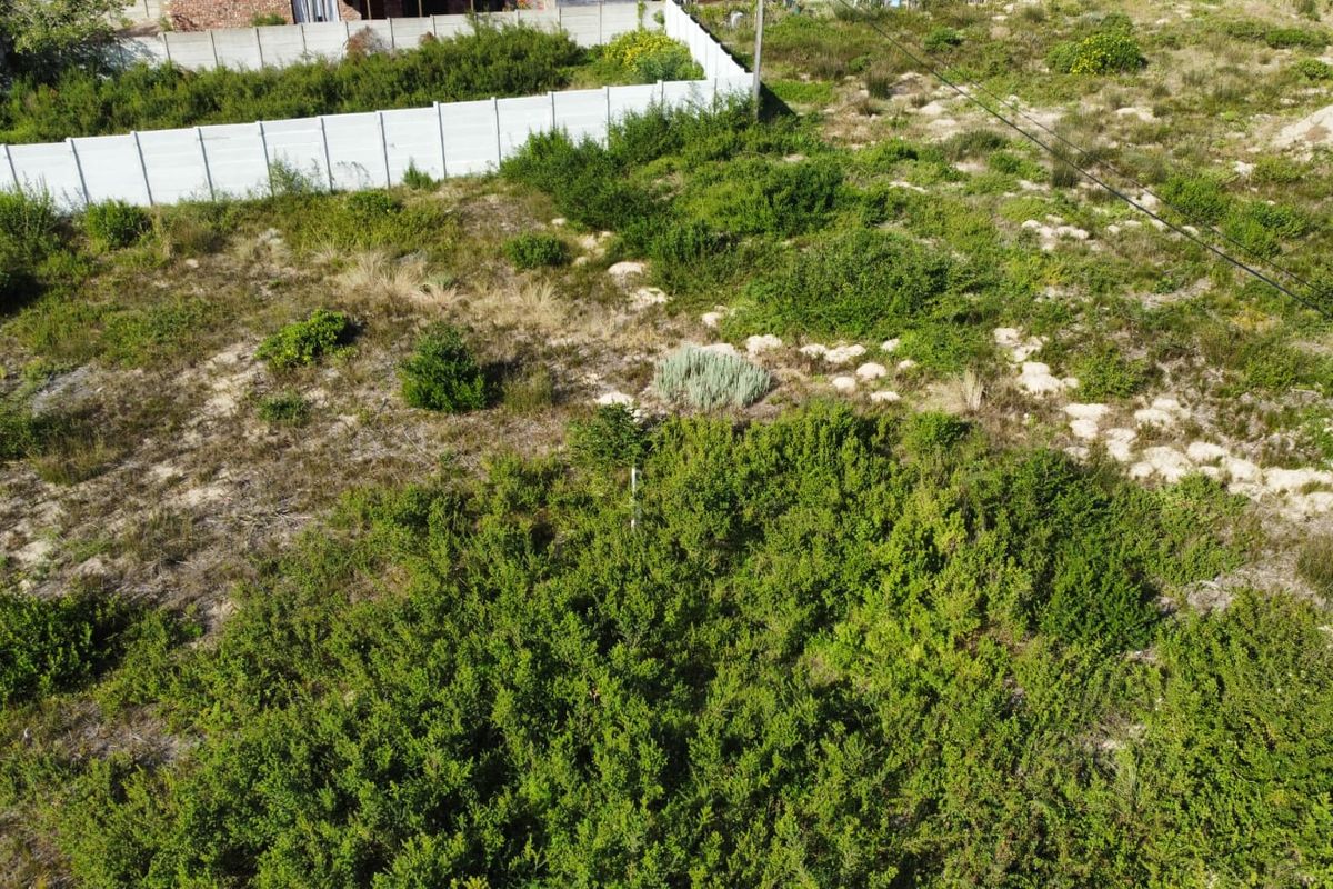 An aerial view of a vacant residential plot featuring natural vegetation and a precast concrete boundary wall along the perimeter.
