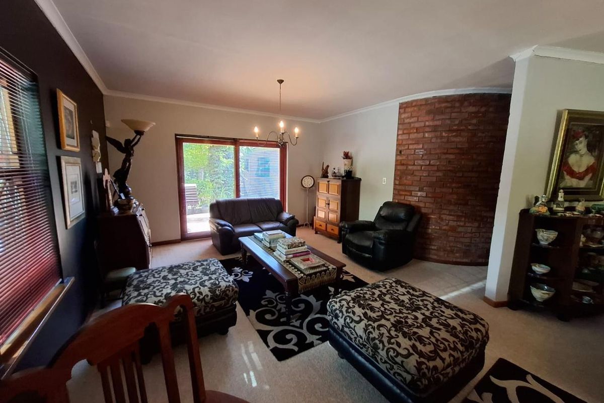 Spacious living room featuring a distinctive curved exposed brick feature wall, carpeted flooring, and a sliding glass door providing access to the outdoor area.