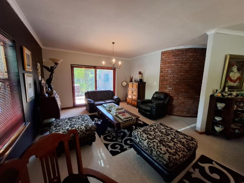 Spacious living room featuring a distinctive curved exposed brick feature wall, carpeted flooring, and a sliding glass door providing access to the outdoor area.
